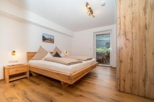 een slaapkamer met een bed en een houten vloer bij Alpenhaus Thurnher in Gaschurn