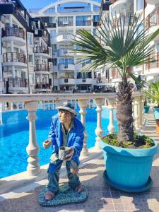 a statue of an old man standing next to a palm tree at Комплекс Виста Дел Мар 2, студио in Sunny Beach