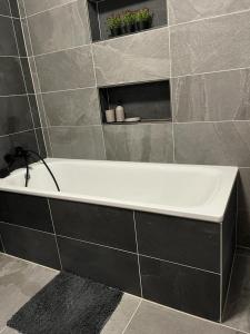 a bath tub in a bathroom with a tile wall at Apartmány Tobias in Běšiny
