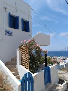 a white building with blue windows and stairs with flowers at Thea Nisaki Mochlos in Mochlos +10 photos