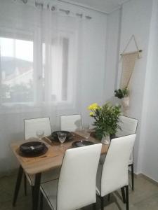 uma mesa de jantar com cadeiras brancas e uma mesa de madeira com em Argostoli Elia's Maisonette em Argostólion