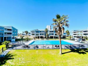 a pool with a palm tree in front of condos at Sea Oats B106 by ALBVR - Great renovation and tons of space in this 2BR 2BA condo - Outdoor Pools, Pier, and Dedicated Beach Access in Gulf Shores