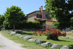 una casa con fiori rossi di fronte a un cortile di Agriturismo Tenuta Serpepe a Marta