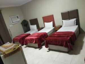 um quarto de hotel com duas camas com lençóis vermelhos em ورده em Al Khobar