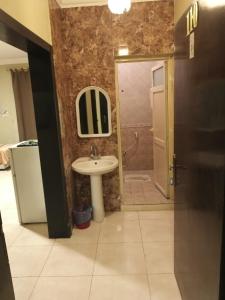 uma casa de banho com um lavatório, um espelho e um chuveiro em ورده em Al Khobar