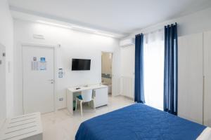 a white bedroom with a blue bed and a desk at B&B BISCEGLIE in Bisceglie
