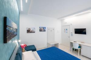 a white room with a blue bed and a desk at B&B BISCEGLIE in Bisceglie
