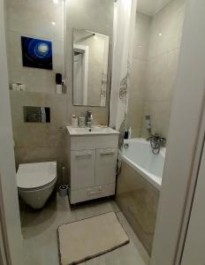een badkamer met een toilet, een wastafel en een bad bij Nice apartament with small tub in Warschau