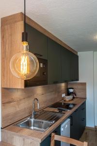 Una cocina con fregadero y lámpara colgante. en Apartments Ciasa Colz, en La Villa