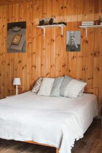 1 dormitorio con 1 cama blanca y paredes de madera en Margarita's cottage, en Jūrmala