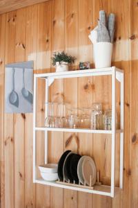 un estante blanco con platos y utensilios en la pared en Margarita's cottage, en Jūrmala