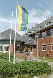 a person standing in front of a house with a flag at Jugendherberge Hörnum in Hörnum