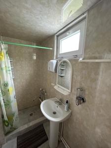 ein Bad mit einem Waschbecken, einem Spiegel und einem Fenster in der Unterkunft Shio's Stonehouse in Tusheti in Tusheti