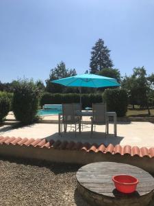 a patio with a blue umbrella and a table and chairs at Les Vents d’Anges in Clussais-la-Pommeraie