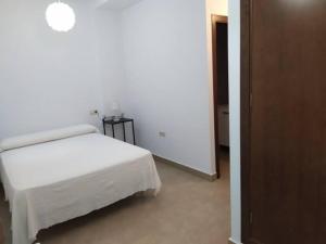 1 dormitorio con 1 cama blanca en una habitación en Apartamentos Centro El Rompido en El Rompido