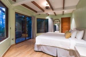 Schlafzimmer mit einem großen weißen Bett und großen Fenstern in der Unterkunft Koora Monteverde-a Cloud Forest Hotel by Sandglass in Monteverde Costa Rica