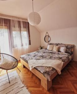 1 dormitorio con 1 cama grande y 1 silla en Vikendica pod kulom, en Vršac