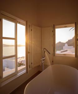a bath tub in a bathroom with two windows at Elia Family Suites in Fira