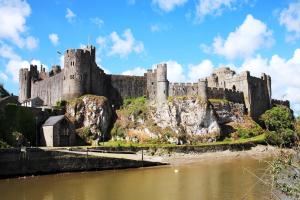 a castle on a hill next to a body of water at Cosy Moat House Cottage #3 in Pembroke