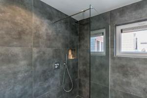 een badkamer met een douche en een glazen deur bij Fika in Renesse