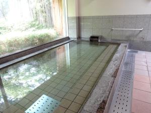 a bathroom with a pool of water with a window at Natsukashiya Fuwari in Nikko