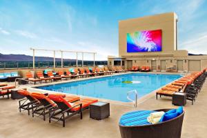 Enticing Stay at Strat Casino STRIP Las Vegas في لاس فيغاس: مسبح كبير مع كراسي وتلفزيون