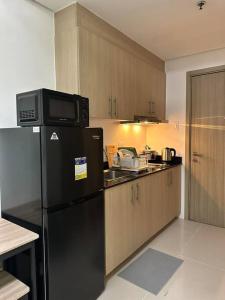 a kitchen with a black refrigerator and wooden cabinets at Night Blink Staycation and Rentals in Manila
