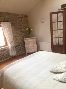 a bedroom with a large white bed and a dresser at Les Vents d’Anges in Clussais-la-Pommeraie