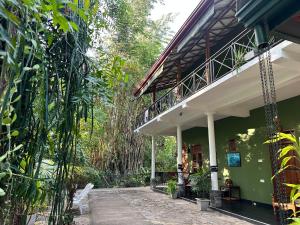 a green building with a porch and a balcony at Nature House in Udawalawe