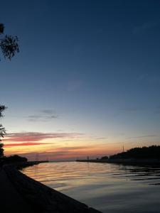 una puesta de sol sobre un cuerpo de agua en Domek ,, Daglezja ” en Dziwnów