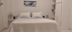 ein weißes Schlafzimmer mit einem Bett mit weißer Bettwäsche und Kissen in der Unterkunft JB Villa in Mesariá