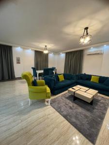 a living room with a blue couch and yellow chairs at Modern Apartment 3 room in Sheikh Zayed N5 الشيخ زايد in 6th Of October