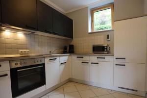una cocina con armarios blancos y horno negro en Property in Daun, en Daun