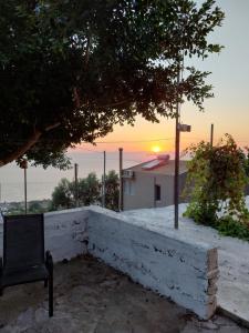 een stoel op een muur met een zonsondergang op de achtergrond bij Paradise lost in Kalamata