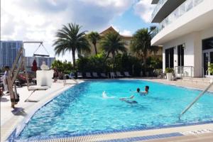a group of people swimming in a swimming pool at Sunlit BeachWalk Studio, 2 Full Beds, Coastal Charm in Hallandale Beach