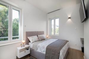 a white bedroom with a bed and two windows at Lalù in Split