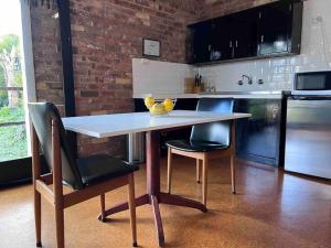 eine Küche mit einem Tisch, 2 Stühlen und einer Theke in der Unterkunft The Coachhouse in Goulburn