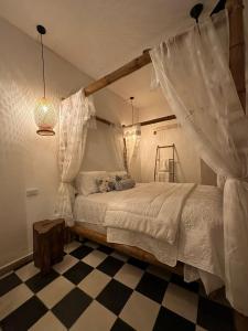 カルタヘナ・デ・インディアスにあるCasa Teresa Hotelのチェッカー付きの床、カーテン付きのベッドが備わるベッドルーム1室が備わります。