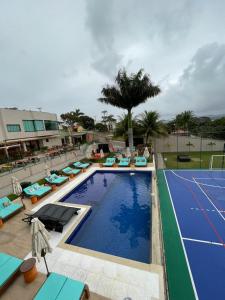 a large swimming pool with chairs and a tennis court at VIVER Pousada Club & Restaurante in Saquarema
