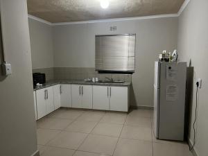 una cucina con armadietti bianchi e frigorifero di Sunset lodge a Manguzi