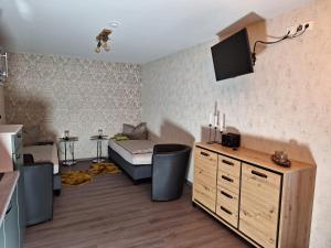 uma sala de estar com um sofá e uma televisão na parede em Pension Eichsfeld Zimmer 2 Komfort em Breitenworbis