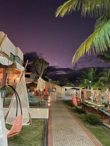 a resort patio with chairs and tables at night at VIVER Pousada Club & Restaurante in Saquarema