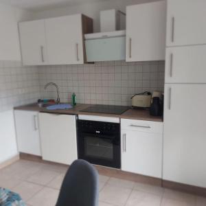 una cocina con armarios blancos y horno negro en Beauty Apartment near Messe City and Airport with Garden en Colonia