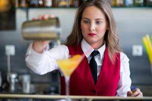 a woman bartender making a cocktail in a bar at Delphi Art Hotel by Prima Hotels in Athens