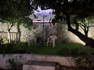 two chairs and a table with an umbrella in a yard at Theoni's Village Apartment II in Kalamata
