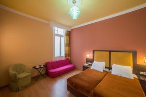 a bedroom with a bed and a pink couch at Delphi Art Hotel by Prima Hotels in Athens