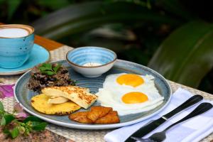 a plate of food with eggs and meat on a table at Koora Monteverde-a Cloud Forest Hotel by Sandglass in Monteverde Costa Rica