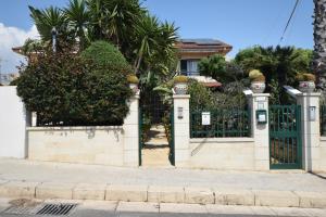 um portão em frente a uma casa com árvores em Casa del sole e del mare em Marina di Ragusa