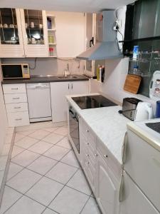 a kitchen with white cabinets and white tile floors at Split Ruža Apartment in Split