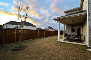 a house with a fence and a bench in a yard at Calming 4-bedroom with fireplace & game room in Little Elm